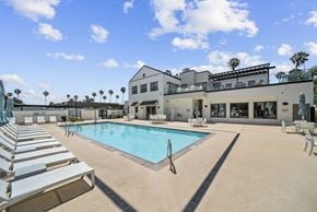 Goleta apartment for rent - A swimming pool with sun loungers and a building in the background.