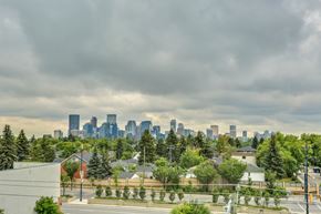Calgary apartment for rent - the skyline of the city with trees in the foreground and a road