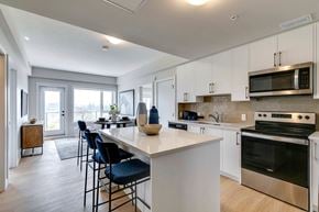 Calgary apartment for rent - a kitchen with white cabinets and a large white island with blue chairs at shawnessy station