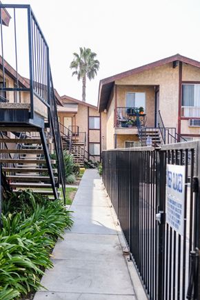 Anaheim apartment for rent - A black fence with a sign on it borders a sidewalk.