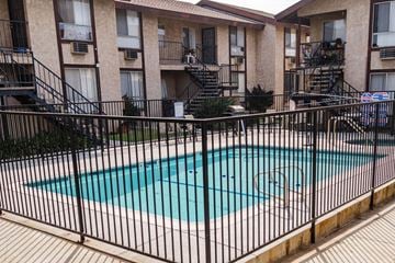 Anaheim apartment for rent - A black fence surrounds a small pool in front of apartment buildings.