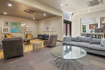 San Jose apartment for rent - A modern living room with a glass table and grey couches.