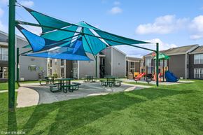 Tampa apartment for rent - A playground with a blue and green umbrella and picnic tables.