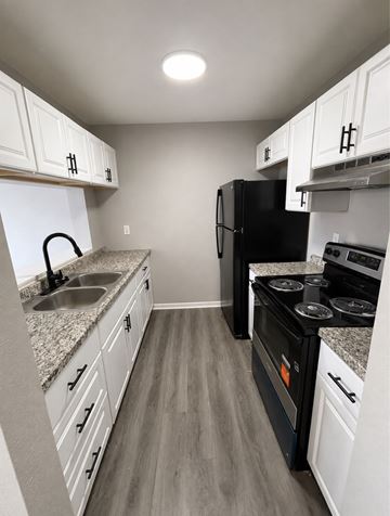 Clearwater apartment for rent - A black refrigerator sits in a kitchen with white cabinets and a granite countertop.