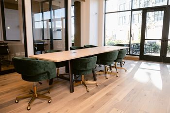 Long conference room with table and green chairs