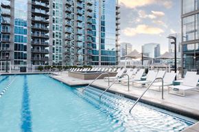 Nashville apartment for rent - A swimming pool with lounge chairs and a view of a city skyline.