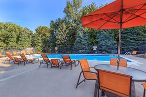 Indianapolis apartment for rent - A pool area with orange chairs and a red umbrella.