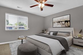 Indianapolis apartment for rent - A bedroom with a large bed, a ceiling fan, and a window with blinds.