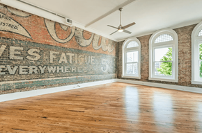 Knoxville apartment for rent - an old mural on a brick wall in an empty room with hardwood floors and a ceiling