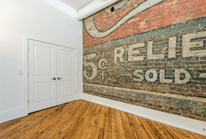 Knoxville apartment for rent - an old sign on a brick wall in a room with wooden floors and a white door