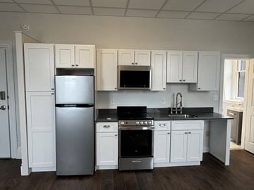Portsmouth apartment for rent - A kitchen with white cabinets and a black countertop.