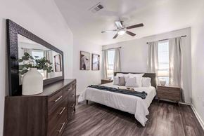 Austin apartment for rent - A bedroom with a bed, dresser, mirror, and a ceiling fan at 95twenty Apartments, Texas