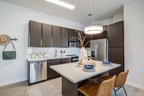 Broomfield apartment for rent - a kitchen with a large island and stainless steel appliances at Arista Uptown  Apartments, Broomfield, CO