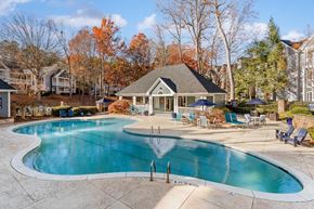 Alpharetta apartment for rent - A large outdoor swimming pool surrounded by a patio area with chairs and umbrellas.