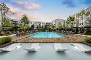 Hyannis apartment for rent - A large pool with lounge chairs and a building in the background.