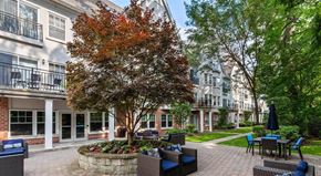 Bronxville apartment for rent - a courtyard with tables and chairs and a tree in front of a building