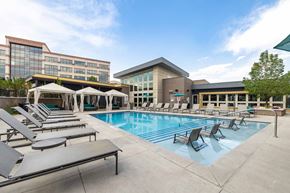 Denver apartment for rent - A pool area with sun loungers and a building in the background.