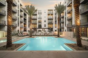 Tempe apartment for rent - A swimming pool surrounded by palm trees and apartment buildings.