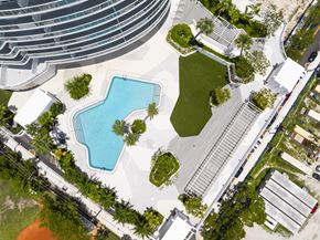Miami apartment for rent - A swimming pool surrounded by a grassy area and trees.