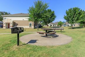 Dallas apartment for rent - a park with a picnic table and benches in front of a building