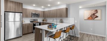 Nampa apartment for rent - A modern kitchen with a refrigerator, microwave, oven, and a dining table with chairs.