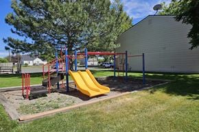 Pocatello apartment for rent - A playground with a yellow slide and red and blue equipment.