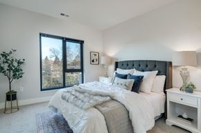 Brookfield apartment for rent - A bedroom with a large bed, a nightstand, and a window with a view of trees.