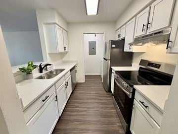 Janesville apartment for rent - A kitchen with white cabinets and a black fridge.