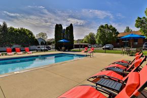 Milwaukee apartment for rent - A pool surrounded by red chairs and a blue umbrella.
