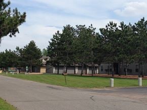 Wausau apartment for rent - A road with a building and trees in the background.