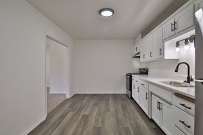 De Pere apartment for rent - A kitchen with white cabinets and a wooden floor.