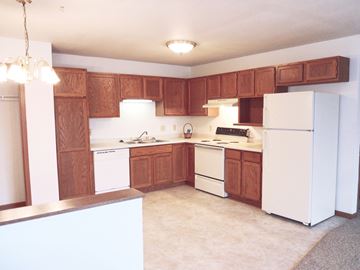 Richland Center apartment for rent - A kitchen with white appliances and wooden cabinets.