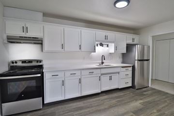 De Pere apartment for rent - A modern kitchen with white cabinets and a black stove top oven.
