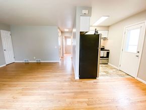 Madison apartment for rent - an empty living room and kitchen with wood floors and a refrigerator