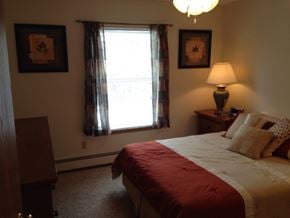 Wausau apartment for rent - A bedroom with a bed, nightstand, and window.