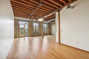 Milwaukee apartment for rent - an empty living room with wood floors and exposed brick walls