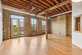 Milwaukee apartment for rent - an empty living room with exposed brick walls and wood floors