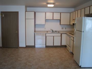 Sheboygan Falls apartment for rent - A kitchen with white appliances and brown cabinets.