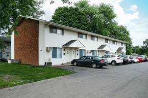 Sun Prairie townhouse for rent - A parking lot with cars parked in front of a white building with a red brick chimney.