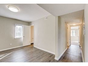 Oconomowoc apartment for rent - a spacious living room with wood floors and a door to a hallway