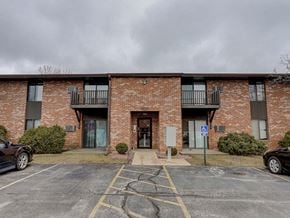 Appleton apartment for rent - A parking lot in front of a brick building with a blue sign.
