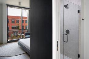 Los Angeles Ca 90028 apartment for rent - A modern bedroom with a large bed and a glass door leading to a balcony.