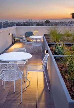Los Angeles Ca 90028 apartment for rent - A patio with a table and chairs overlooking a cityscape at sunset.