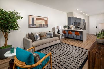Azusa apartment for rent - A living room with a grey couch, a blue chair, and a painting on the wall.