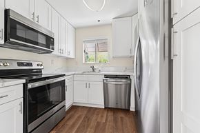 Palm Springs apartment for rent - Updated kitchen in Cielo apartment home with plank flooring, white shaker cabinets, quartz countertops, updated appliances, and a charming window leading to courtyard.