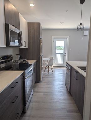 Miramichi apartment for rent - A kitchen with dark wood cabinets and a white counter.