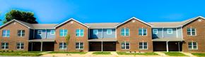 Kokomo triplex for rent - a large brick house with a blue sky in the background