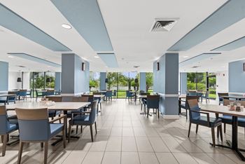 A large cafeteria with tables and chairs and a tiled floor.