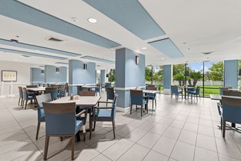 A large room with tables and chairs and a blue ceiling.