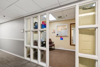 A room with a white door and a brown carpet.